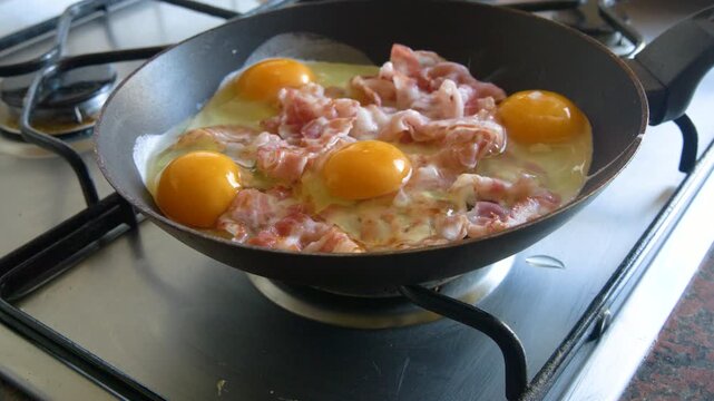 Cooking fried eggs with bacon in frying pan