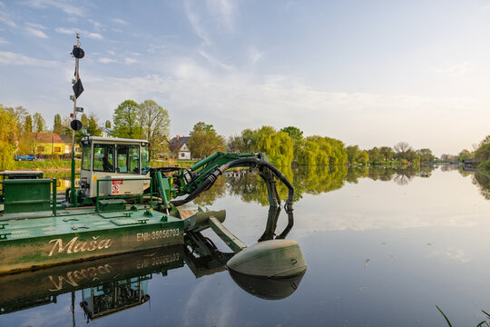 Green Watermaster Dredger Boat Performing River Dredging Near Riverside Village With Calm Reflections, Vinkovci, Croatia