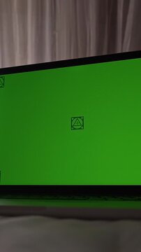 Vertical video. Open Laptop with Green Screen on Bed in Cozy Bedroom During Early Morning. Technology Mockup, Remote Work, Digital Lifestyle Concept