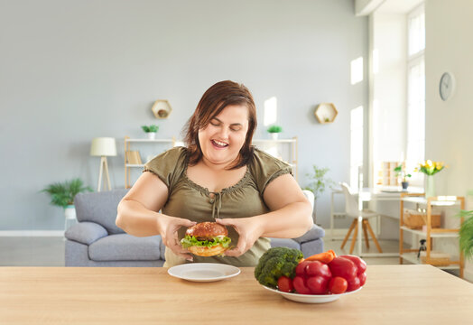 Overweight obese hungry happy woman with excessive fat eating unhealthy fast food, tasty hamburger, juicy burger, cheeseburger, chubby plus size big fat fit lady good appetite gets excess calories