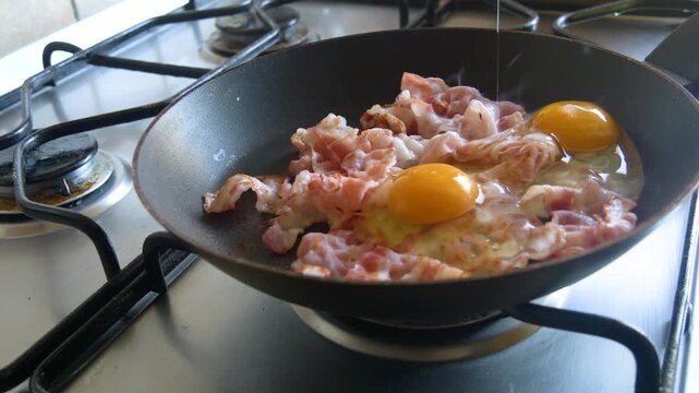 Homemade breakfast with eggs and bacon cooking