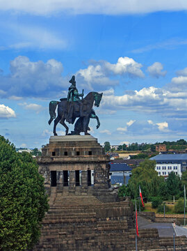 Elevated view from the hilltop of  Ehrenbreitstein Fortress of King Wilheim I Equestrian Statue located on German Corner in Koblenz against a blue cloudy sky