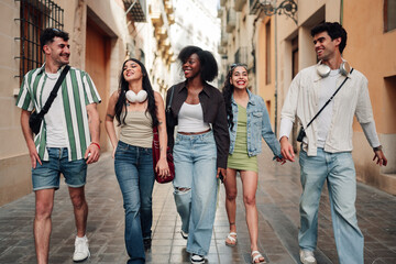 Fototapeta premium Diverse young friends walking, smiling, and enjoying city life together on a summer urban street