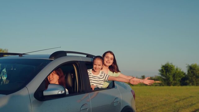 Woman mother child driving car, kid boy girl waving their hands out car window, happy family cheerful people childhood, carefree childhood moments leaning from windows during road trip fun, country
