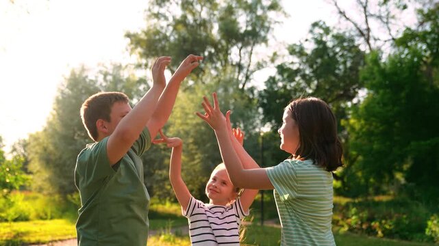 Happy children playing playground, children hands sun glare nature, boy girl friends playground, energetic children playing under soft evening sun, young friends having fun outside in summer, playtime