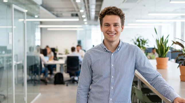 Happy male office worker wearing striped shirt, professional business portrait with confident smile, career development and modern workplace concept