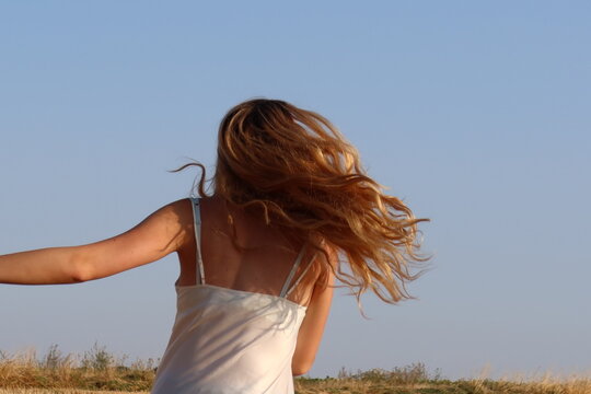 fille avec cheveux dor&eacute;s au soleil dans le champ