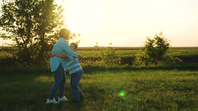 Woman hugging little boy son sunset nature, child kid hugging mother outdoors, run happy family, silhouette people, child parent run hugging nature sunset, backlit warm glow, family outdoor hug