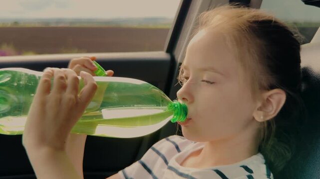 Close up of girl with water bottle, Hydrating while on the move, Transporting a hydrated traveler, Road adventures with children, Summertime family road trip, Child safety and comfort in car