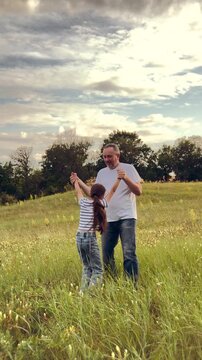 happy family, children dream fun fly, kid with father playing outdoors, Outdoor play and laughter, child and parent together, jeans and striped shirt style, wide open space, safety and trust displayed