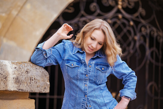 Pensive middle aged woman leaning against stone arch outdoors. Concept of urban architecture, travel and peaceful mood.