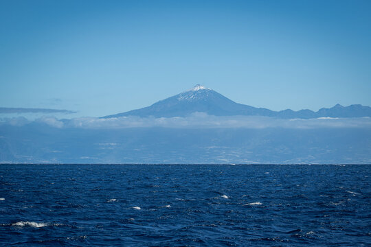 Snow-capped Mount Teide volcano on Tenerife rising above the deep blue Atlantic Ocean seen from the sea Canary Islands