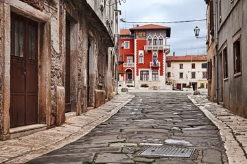 Vodnjan, Istria, Croatia: Narrow street leading to the ancient People Square (Trg Narodni) near Pula, featuring the neo-gothic facade and balcony of the red city hall © ermess