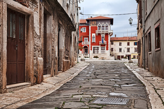 Vodnjan, Istria, Croatia: Narrow street leading to the ancient People Square (Trg Narodni) near Pula, featuring the neo-gothic facade and balcony of the red city hall