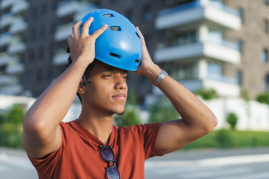 Man puts on a blue helmet while preparing to ride a bicycle in the city