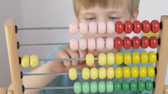 Close up of wooden abacus with colorful beads moving during counting exercise. Practical mathematics activity supporting STEM learning, logical thinking and early childhood education concept. 