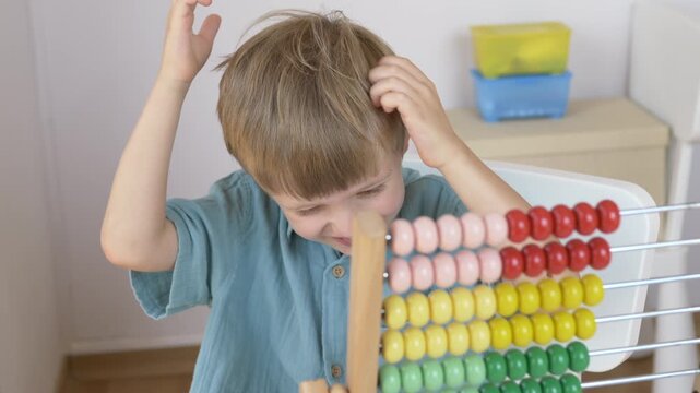 Boy smiles and laughing happily beside colorful bead abacus showing joy and positive attitude during early math learning. Happy back to school and motivated child concept.