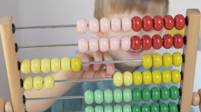Colorful wooden abacus helps child practice counting and simple arithmetic during educational play at home. Fine motor development, mathematical thinking and concentration concept. 