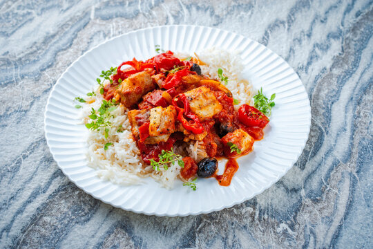 Slow cooked fish stew with rice, tomato souce and vegetables served as close-up on a design plate