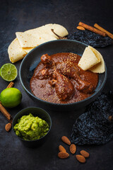 Traditional authentic artisan spicy chicken mole poblano in a bowl with avocado guacamole and fresh...