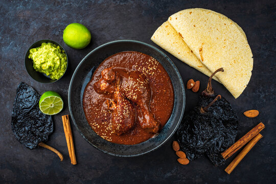 Traditional authentic artisan spicy Mexican chicken mole poblano in a bowl with avocado guacamole and fresh tortilla served 