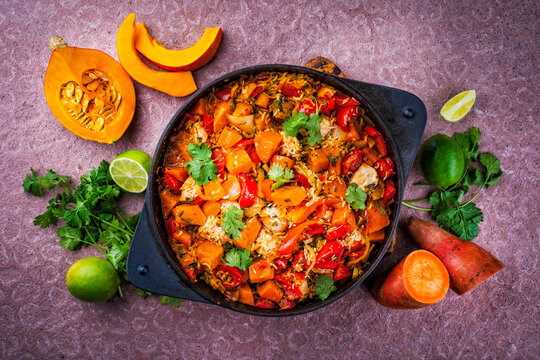 Slow cooked casserole dish healthy yummy spicy Italian one-pan role stew vegetable pumpkin, sweet potato, chicken and rice served as top view in a design casserole
