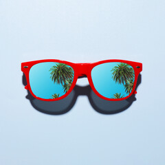 Obraz premium Fashionable sunglasses on light background. Tropical palm trees and blue sky reflecting in lenses
