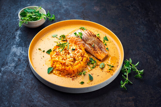 Fried salmon fish fillet with pumpkin and sweet potato rosti gratin served as close-up on a design plate