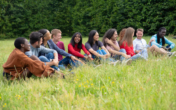 Large Diverse Group of Friends Sitting Together in a Grass Field