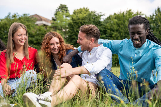 Close-up of Diverse Friends Sitting Together in Grass Laughing