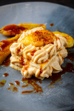 Dessert puff pastry layered mille-feuille with pastry cream and caramelized banana with butter caramel sauce served as close-up on a design plate