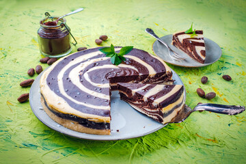 Obraz premium Artisan homemade baked zebra black-white cheesecake pie with dark chocolate served as close-up on a cake plate