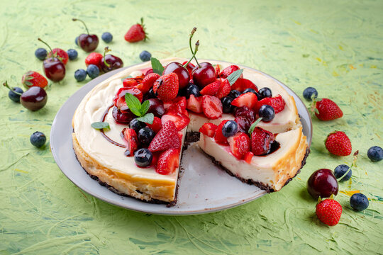 Artisan homemade New York cheesecake pie with fresh strawberries, blueberries and cherries and balsamic cream sauce served as close-up on a design plate