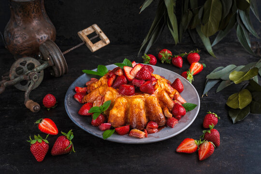 Artisan homemade baked cheesecake pudding pie with fresh strawberries and caramelized rhubarb compote topping served as close-up on a design cake plate