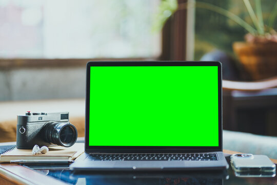 Mockup of laptop computer with empty screen of coffee, modern smartphone, wireless earbuds, notebook, a pen, classic black rangefinder camera morning sunlight.