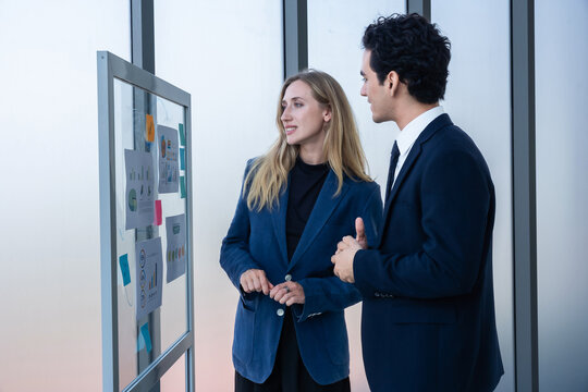 Two businessman and businesswoman partners  in suits smiling standing Talking Discussing presenting financial graph Concept on flip chart board  business expressed embolden and successful concept.