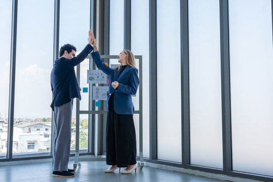 Two businessman and businesswoman partners  in suits smiling standing Talking Discussing presenting financial graph Concept on flip chart board  business expressed embolden and successful concept.