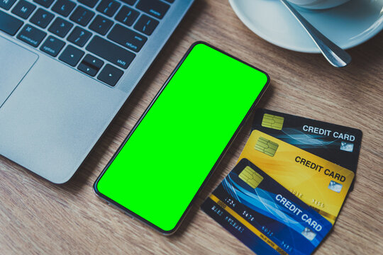 Credit card of laptop computer, smartphone empty screen and coffee cup on wooden background,Online banking Concept,Green screen