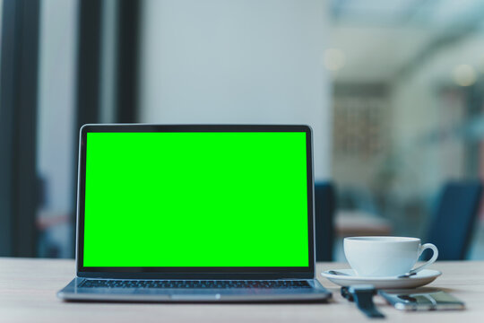 Mockup of laptop computer with empty screen with coffee cup and smartphone ,smartwatch on table of the coffee shop background,Green screen