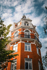 Low Angle View of Classic Red Brick Apartment Building with Balcony and Turret © Calvin