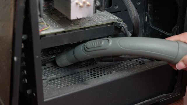 Cleaning dusty desktop computer interior with vacuum cleaner. Technician performing maintenance and service by vacuuming thick dust from the internal components of a personal computer