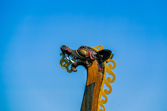 Carved dragon head figurehead of a Viking ship against blue sky