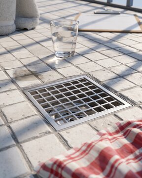 Balcony Drain Cover Inspection with Glass of Water and Clipboard on Tiled Floor
