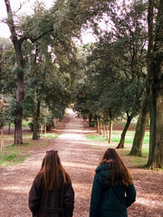 Dwie kobiety spacerujące aleją drzew w rzymskim parku Villa Borghese © Szymon
