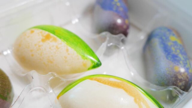 Artisan painted chocolate bonbons in clear plastic packaging tray