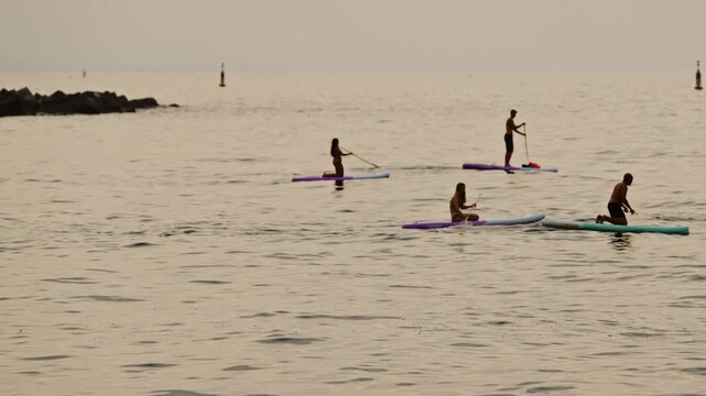 people in shadow paddle surfing in barcelona 