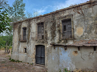 Fototapeta premium Facade of a two story abandoned Spanish manor with wrought iron balconies in Alicante province
