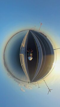 Vertical video. Little Planet View of Motorcycle Ride Across Southern Terminus of Bali Mandara Toll Road at Sunrise, Surrounded by Ocean, Highway and Clear Morning Sky