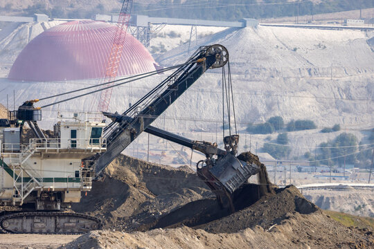 Heavy Dragline Excavator Loading Earth at Open-Pit Mine in British Columbia, Canada With Tailings Dome
