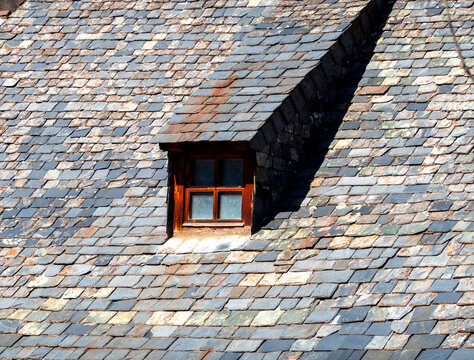 Dormer window on rustic slate roof in sunlight